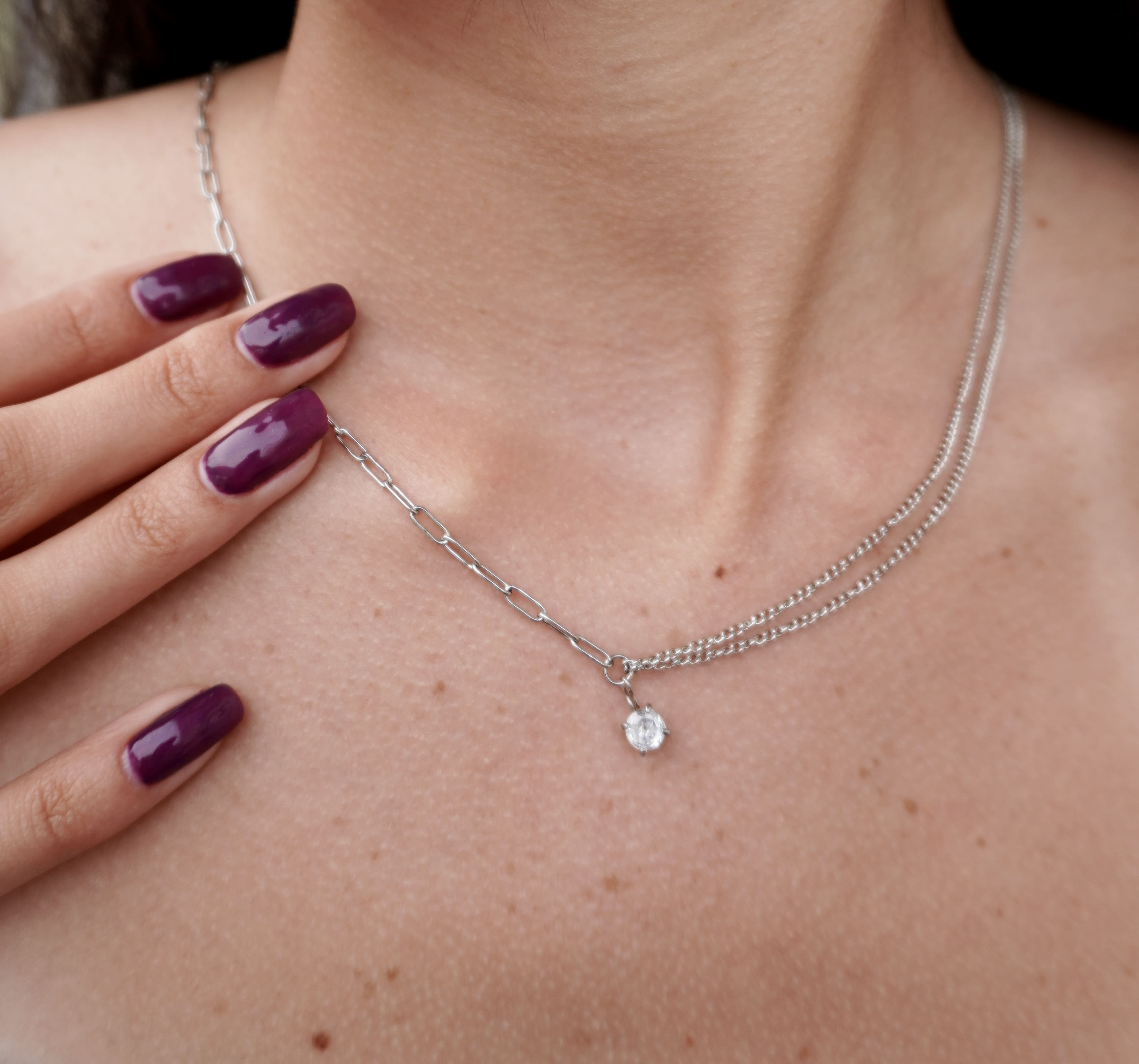 Isara necklace by Mareas worn on skin, a minimalist silver piece with a soft luminous diamond.